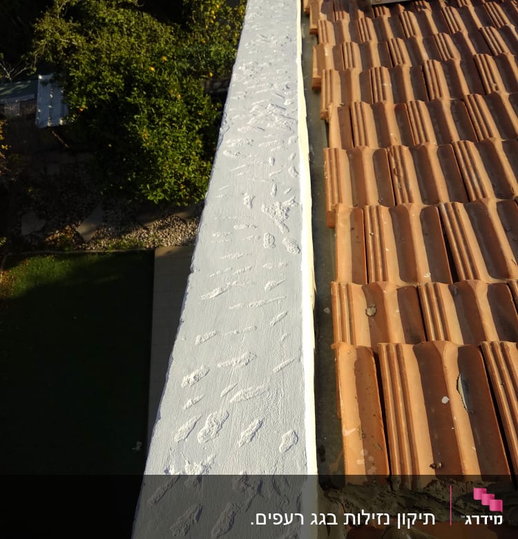 גג רעפים חומים עם קיר בטון צבוע לבן